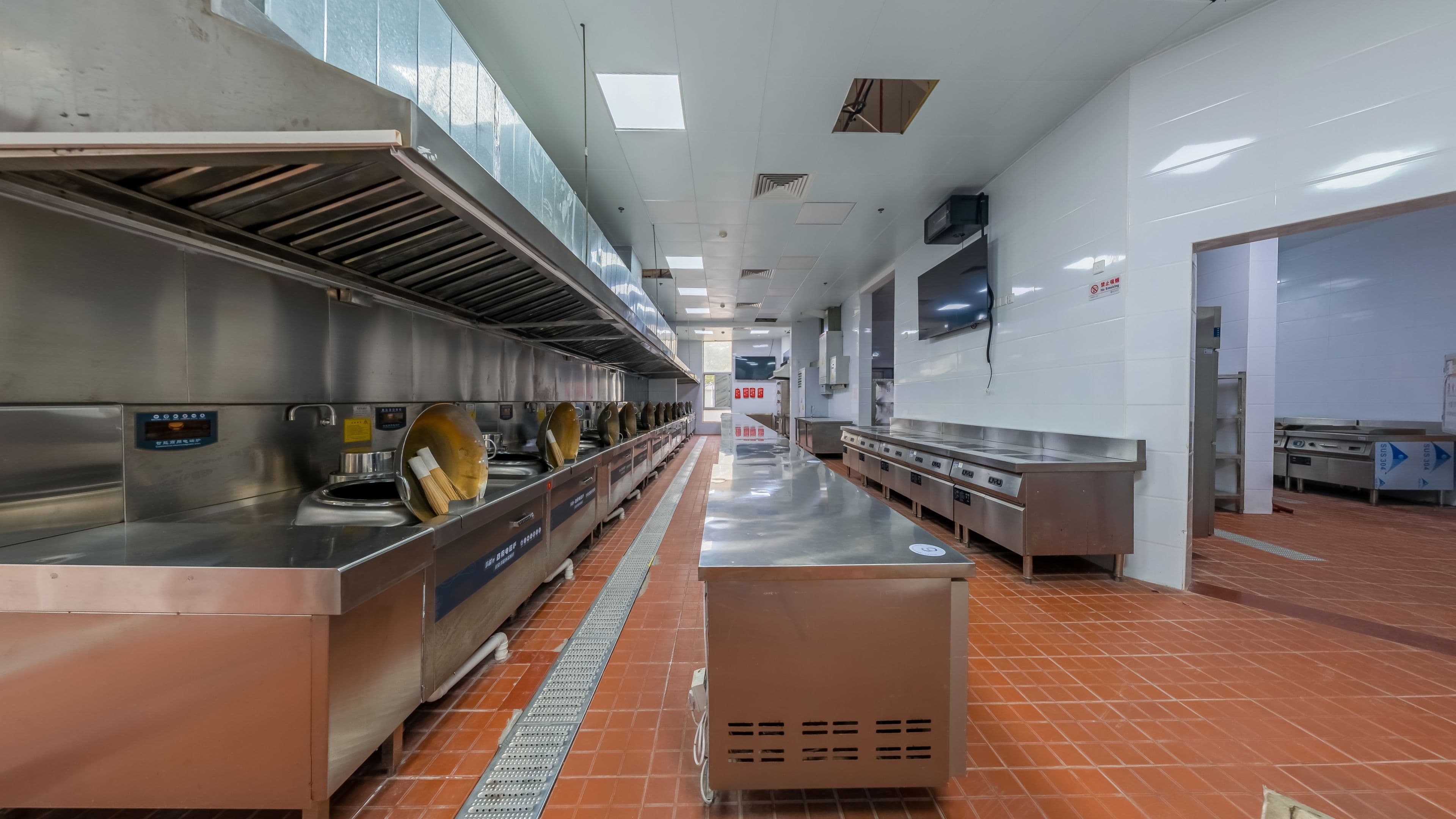 Empty central kitchen in Singapore with stainless steel cooking line and exhaust hoods, ready for reinstatement